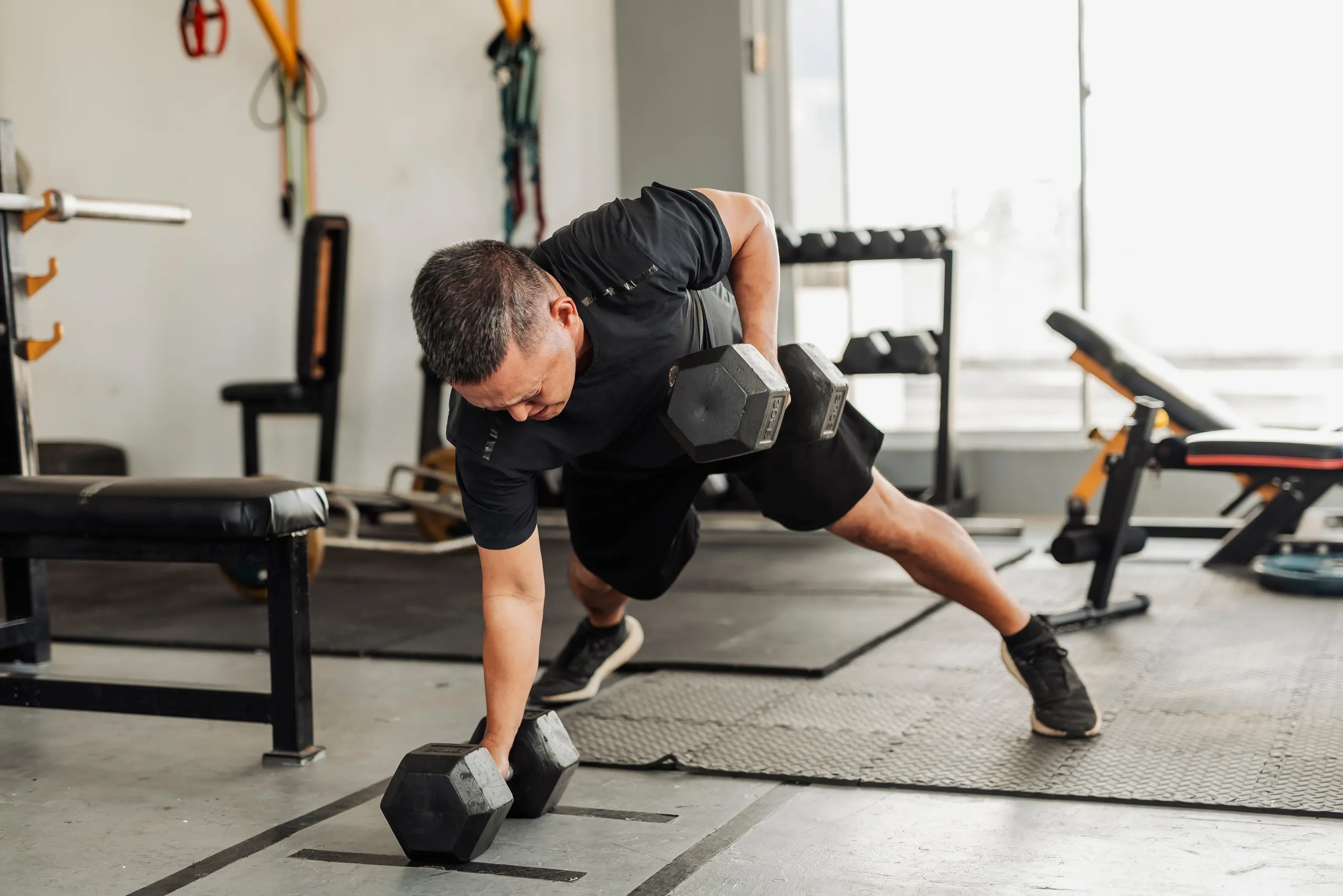 Strength Training with Dumbbells: Men Performing the Renegade Row Exercise at the Gym